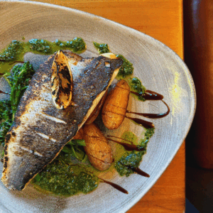 Food offers. Pan-seared seabass with charred broccoli & new potatoes with salsa verde, presented as a comfort dish included in this food off
