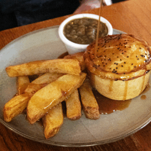 A freshly baked steak and ale pie served with chips and gravy, highlighting comfort food available through these food offers.