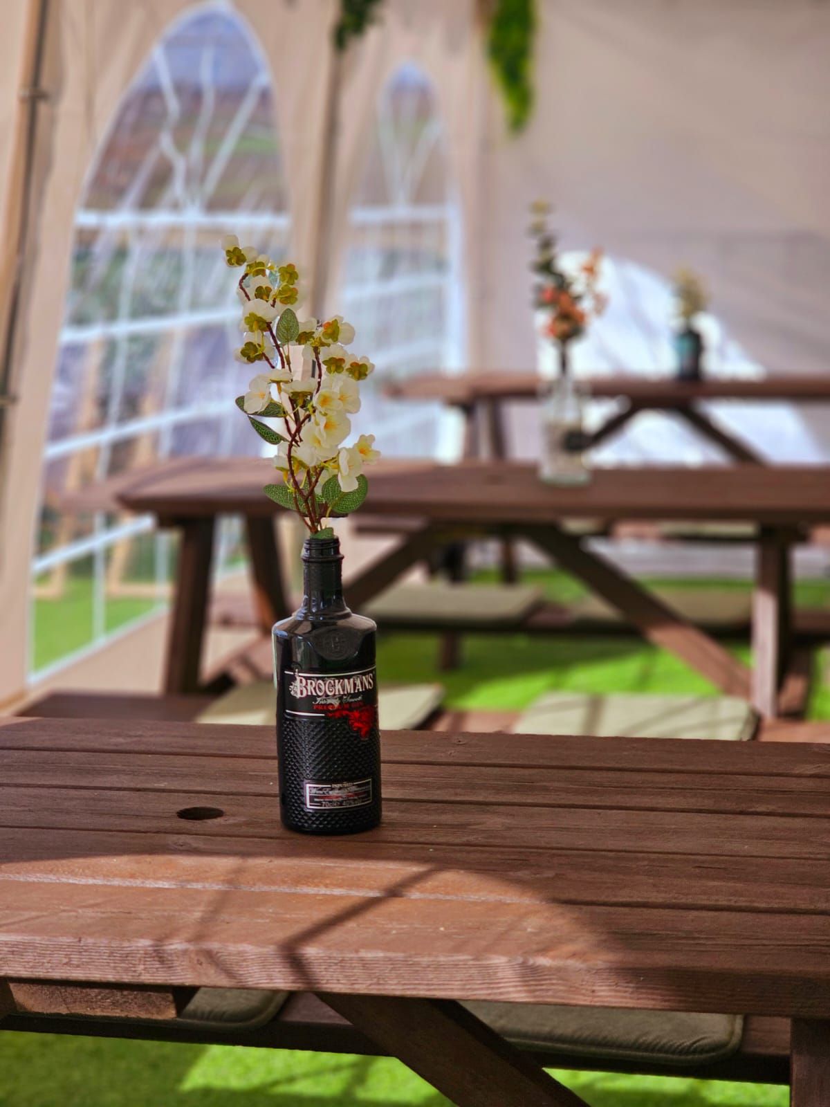A beautiful floral display inside a gin bottle displayed on a bench in the Crown and Anchor marquee